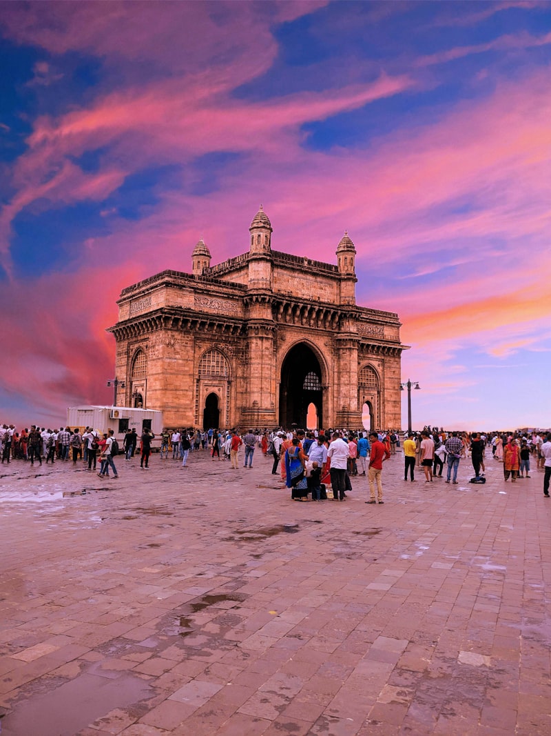 Gateway of India glowing under a pink and purple sunset sky