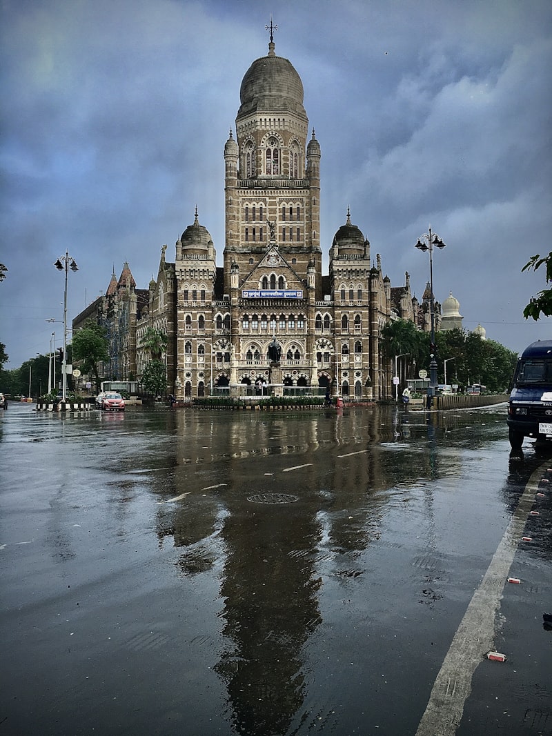 BMC heritage building reflected in monsoon rainwater on the road