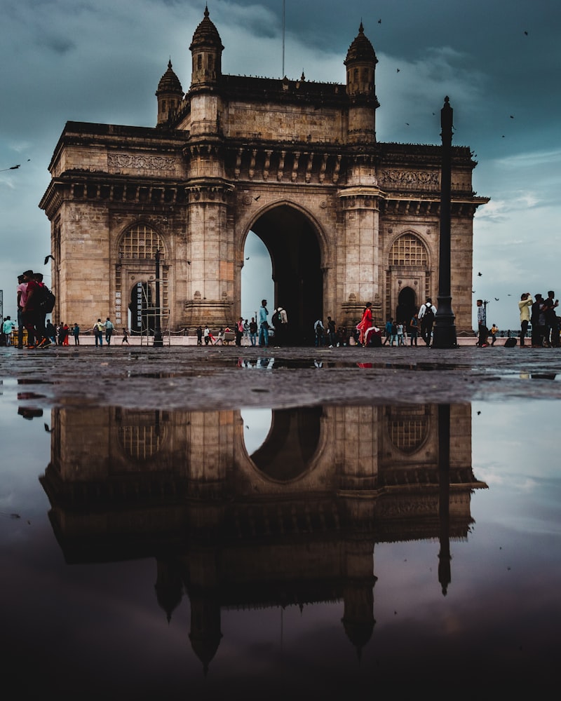 Gateway of India reflected in a rain puddle with moody clouds